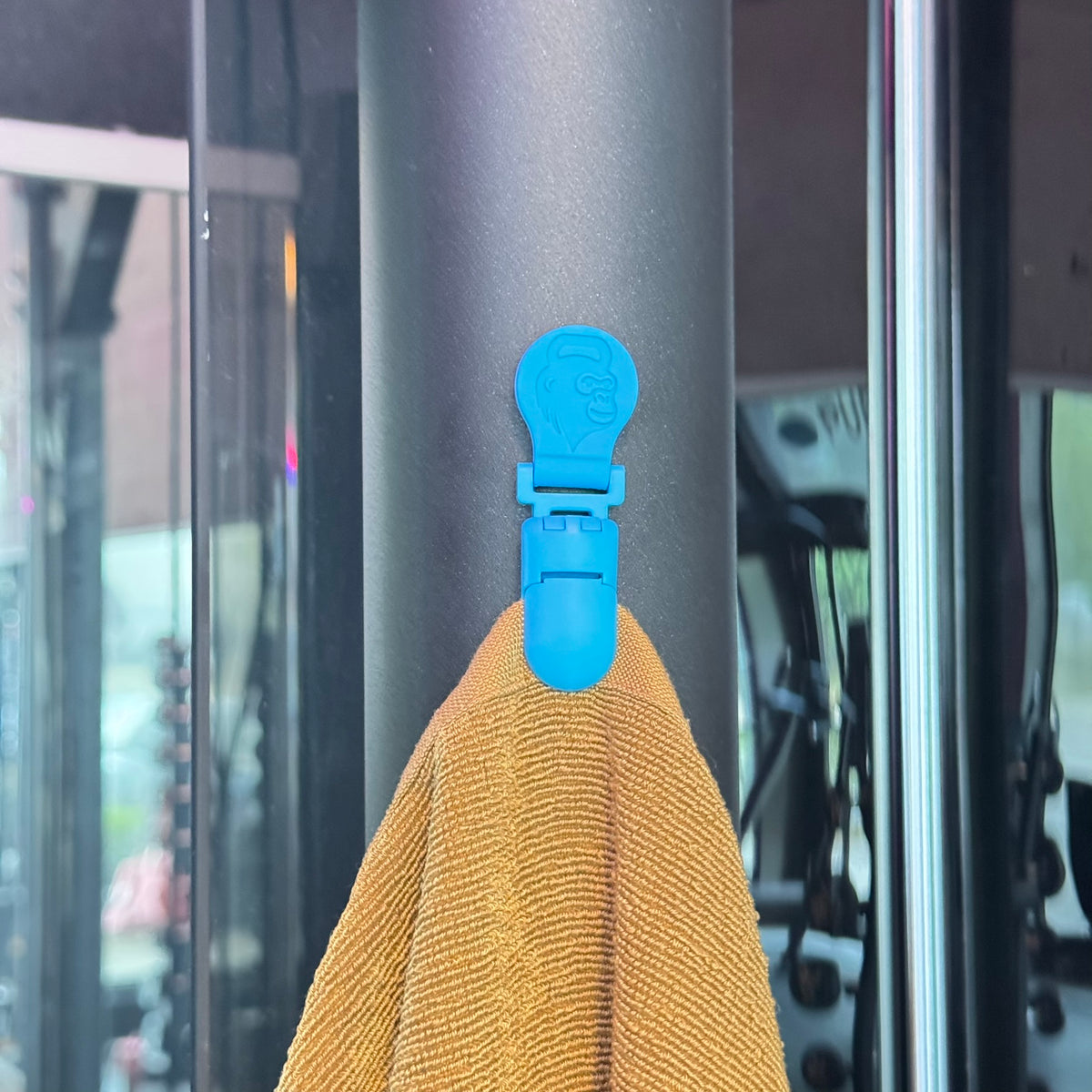 Primo piano del GYMMONKY Magnetic Towel Clip che tiene un asciugamano su un attrezzo da palestra